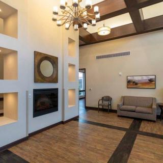 A modern lobby interior featuring a chandelier, comfortable seating area, and artistic wall decor.