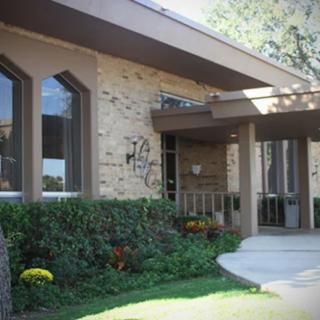 A modern house with large windows and a well-maintained entrance surrounded by greenery.
