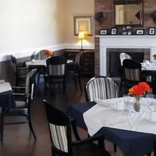 A cozy restaurant dining room with neatly arranged tables and a fireplace.