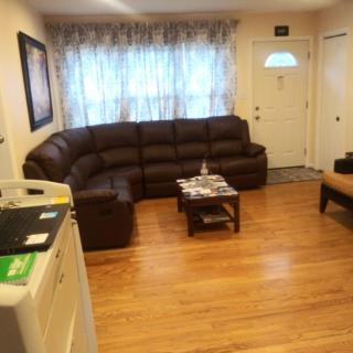 A cozy living room with a large sectional sofa and hardwood flooring.