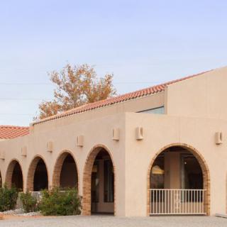 A Mediterranean-style building with stucco walls and a series of arches in a desert landscape.