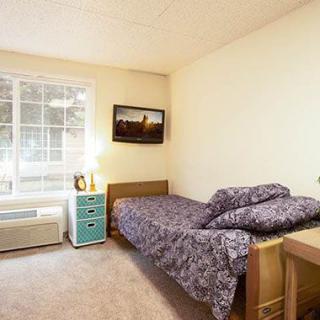 A cozy bedroom with a single bed and a window letting in natural light.