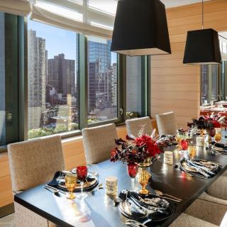 A modern dining room with a city view, elegantly set for a formal meal.