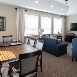 A spacious living and dining area with comfortable seating, a television, and large windows providing ample natural light.