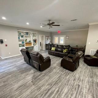 Spacious living room with leather sofas and a ceiling fan, featuring hardwood flooring and built-in shelves.