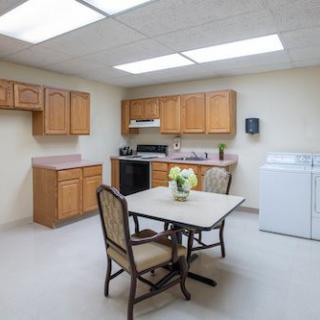 A kitchen with wooden cabinets, a small dining table with chairs, appliances, and a washer and dryer.