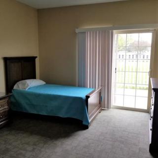A simple bedroom with a single bed and a sliding glass door letting in natural light.
