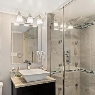 A sleek and modern bathroom featuring a stylish sink, spacious shower enclosure, and elegant lighting.