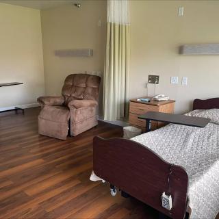 A hospital room featuring a bed, recliner chair, and small table.