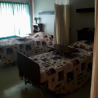 A dimly lit hospital room with two beds separated by a curtain.
