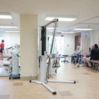 A gym with various exercise equipment and people working out.