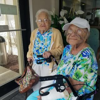 Two elderly women enjoying each other's company with bright smiles and vibrant outfits.