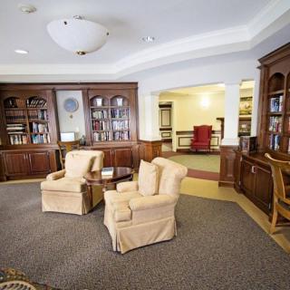 A cozy library room with two armchairs, wooden bookshelves, and a warm ambiance.