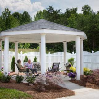 People relaxing under a gazebo in a landscaped garden.