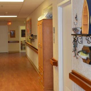 A quiet, well-lit hallway with wooden floors and decorative items on the wall.