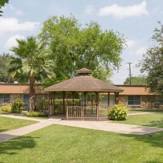 A serene outdoor space with a gazebo surrounded by lush greenery and trees.
