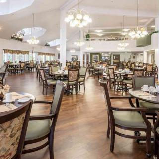 Spacious and elegantly furnished dining area with chandeliers and wooden flooring.