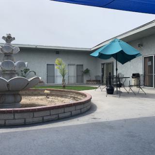 A serene outdoor patio area featuring a decorative fountain and shaded seating.