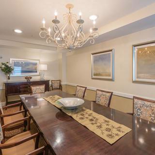 A sophisticated dining room with a long table, chairs, and a chandelier.
