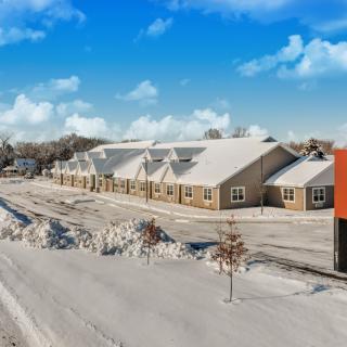 A snowy winter scene with a building and a clear blue sky.