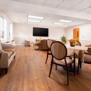 A modern waiting room with comfortable seating, a large TV, and wooden flooring.