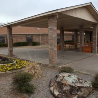 A building entrance with a covered driveway and landscaped surroundings.