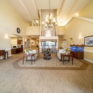 A spacious and modern lobby featuring a central chandelier, comfortable seating, and a fireplace.