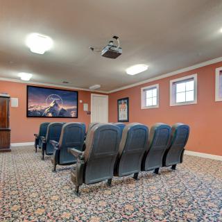 A cozy home theater with rows of seats, a projector, and a screen.