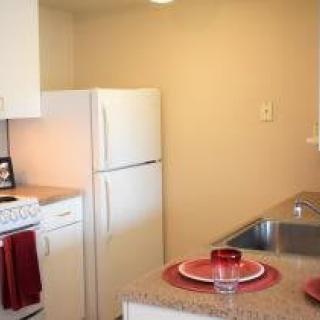 Compact kitchen with white appliances and a small dining area.
