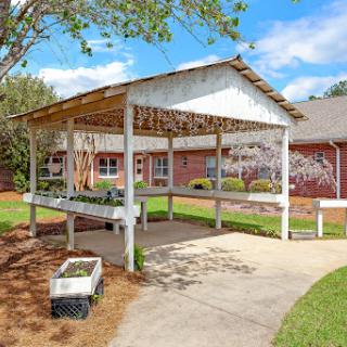 A charming outdoor pavilion surrounded by lush greenery and a clear blue sky.