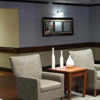 A cozy seating area with two chairs, a wooden table, decorative vases, and a wall mirror.