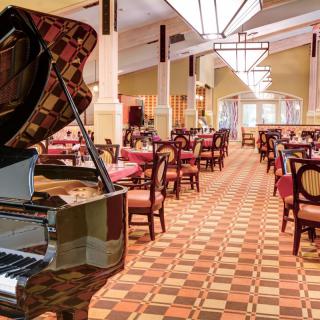 A spacious restaurant interior featuring a grand piano and elegant dining setup.