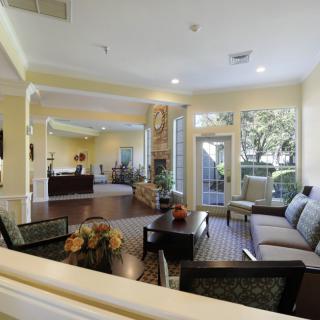 A spacious and well-lit living room with comfortable seating and large windows overlooking a garden.