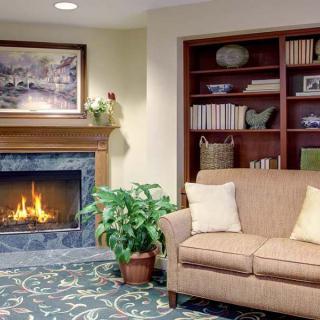 A cozy living room with a fireplace, sofa, and bookshelf.