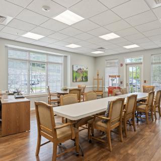 A bright and spacious dining area with tables and chairs, illuminated by natural light through large windows.