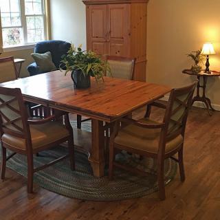 A cozy dining area with a wooden table and chairs, adorned with a plant centerpiece.