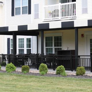 A view of an apartment complex featuring a balcony and well-maintained landscaping.
