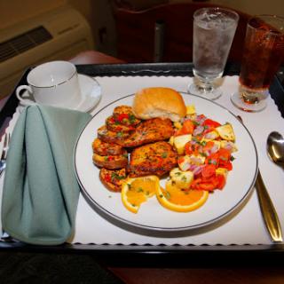 A delicious meal served on a tray, featuring chicken, salad, and beverages.