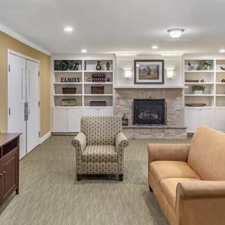 A cozy living room with a fireplace, armchair, and sofa surrounded by built-in bookshelves.