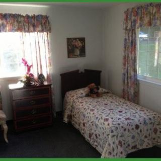 A cozy bedroom with a single bed, floral curtains, and natural lighting.