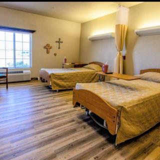 A spacious healthcare room featuring two beds, warm lighting, and a calming atmosphere.