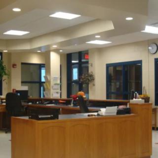A spacious and well-lit office reception area with wooden desks and modern decor.
