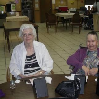 Two elderly women sitting at a table in a dining area.