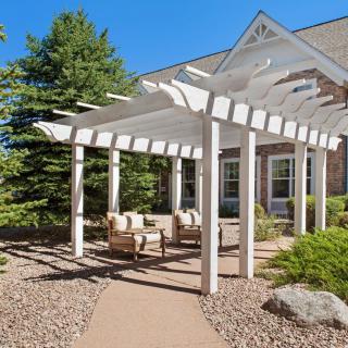 A serene outdoor seating area with a white pergola in a landscaped garden.