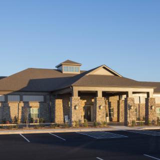 A modern building with a stone facade illuminated by sunset lighting, adjacent to an empty parking lot.