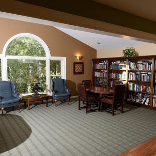 A cozy reading area with bookshelves and comfortable seating next to a large window.