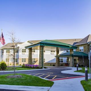 A modern building with a green-roofed entrance and an American flag prominently displayed.