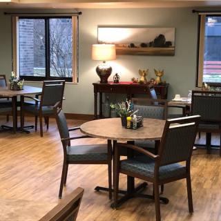 A cozy dining area with neatly arranged tables and chairs, adorned with decorative items and illuminated by warm lighting.