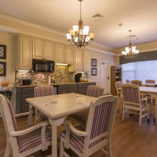 A cozy kitchen and dining area with traditional decor, featuring wooden flooring and elegant chandeliers.