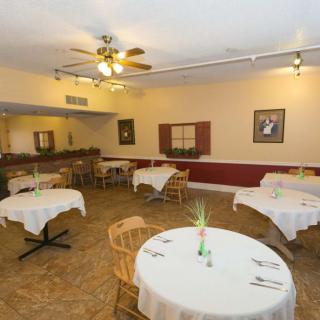 An empty dining area with round tables and wicker chairs, set for customers.